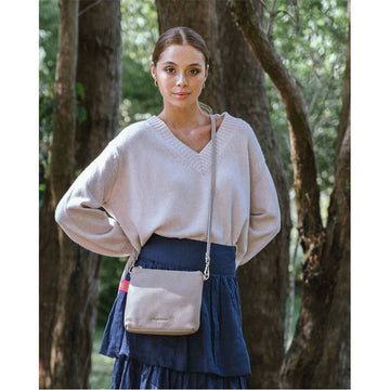 A fawn coloured cross body bag made from leather with a matching strap diagonally across the bag.