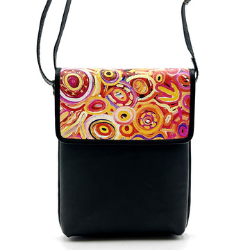 A black leather sling bag printed with artwork by Cedric Varcoe on the flap.