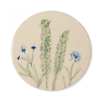 Round ceramic coaster with floral design on a beige background.