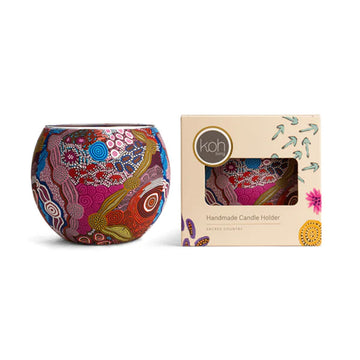 Colourful handcrafted candle holder next to its packaging box on a white background.