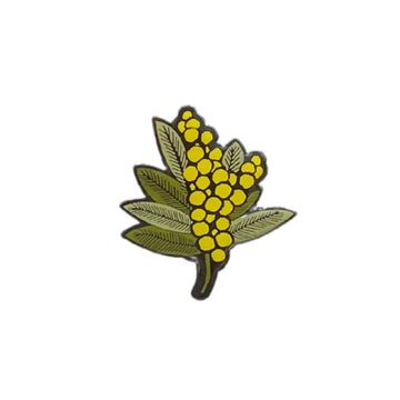 An enamel pin shaped like wattle flowers.