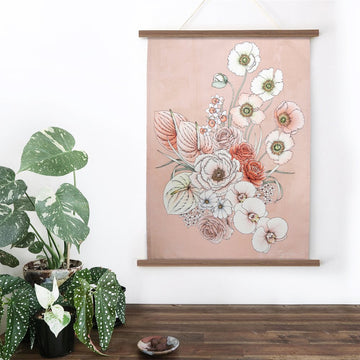 A folded up tea towel in blush illustrated with large pink flowers. There is a white sleeve around the tea towel with product information.