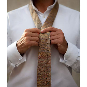 A silk tie in brown printed with a zig zag line design in orange by Doreen Redi Nakamarra.