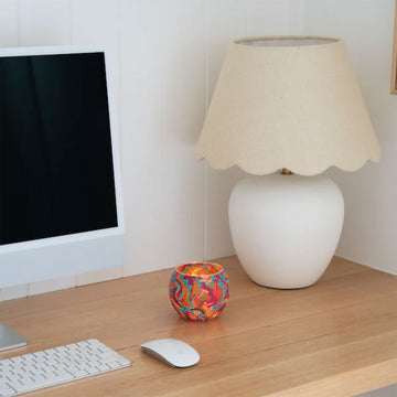 Colourful handcrafted candle holder with packaging on a white background