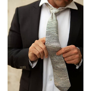 A silk tie rolled up printed with black lines by Walimpirrgna Tjapaltjarri.