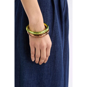 Yellow bangle with blue speckles on a light gray background.