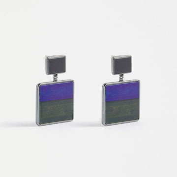 A pair of stud drop earrings with a grey square at the top and a larger square at the bottom with half purple and half grey inside it.