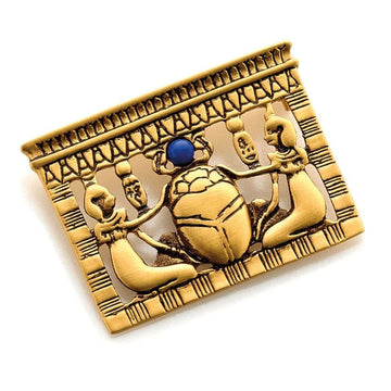 A rectangle gold brooch with an raised etched image of two people placing their hands on a scarab beetle.