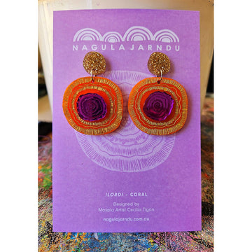 A pair of stud drop earrings with large orange and purple circles attached to a gold glitter stud.