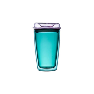 Green glass travel mug with a clear lid on a beige background.
