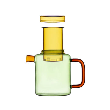 Colorful glass pot with a red handle on a beige background.