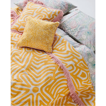 A square cushion in white embroidered with a yellow print.