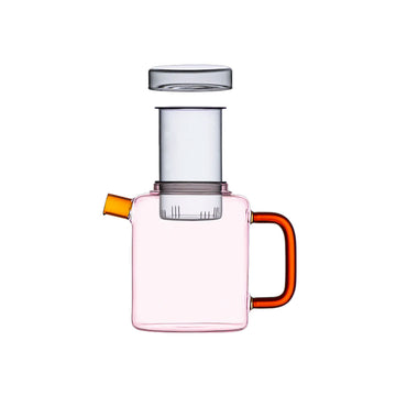 Pink glass pot with a red handle on a beige background.