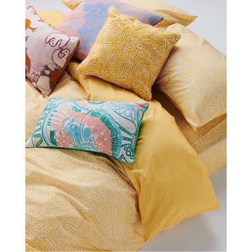 A rectangle cushion embroidered with a design in green, blue and pink.