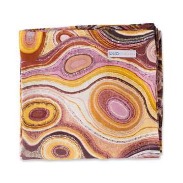 A folded up table cloth printed with Indigenous artwork in shades of yellow and brown.