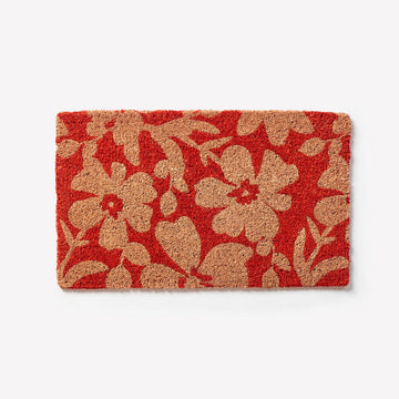 Top down view of a door mat in red printed with brown flowers.