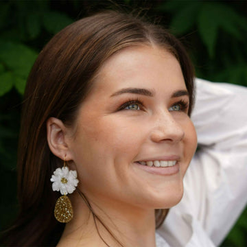 A pair of drop earrings with an white pearl coloured flower and green marble tear drop hanging below.