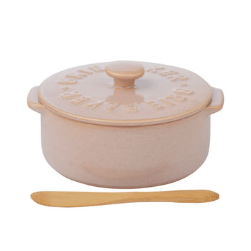 Pink ceramic pot with lid and wooden spoon on a white background.