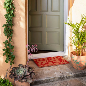 Top down view of a door mat in red printed with brown flowers.