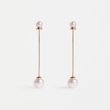 Pair of pearl earrings with gold chains on a white background.