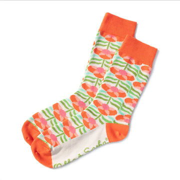 A pair of socks printed with orange flowers on a patterned cream and green background with an orange heel, toe and cuff.