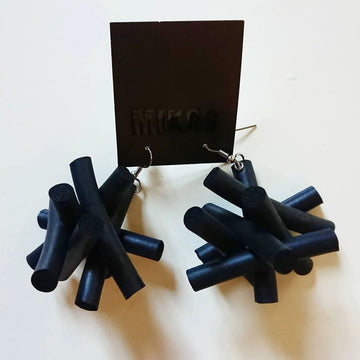 A pair of drop earrings featuring black rubber pieces attached in a messy asterisk shape. 