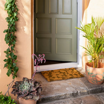 A brown door mat printed with golden brown flowers.