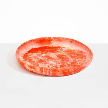 A large shallow bowl made from an orange pink coloured resin.