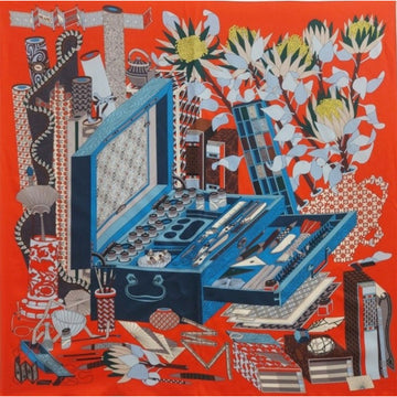 Colorful fabric with a detailed design of tools, flowers, and patterns on a red background.