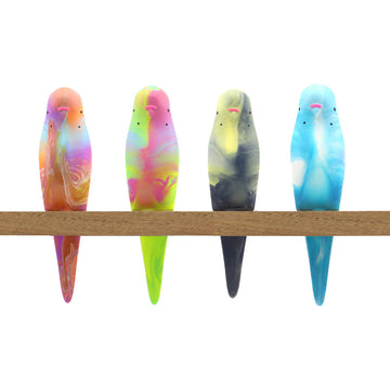 Four resin budgerigar birds in different colours and swirls sitting on a wooden perch.