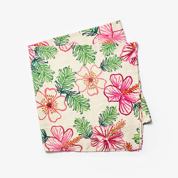 A folded up tablecloth illustrated with pink flowers and green leaves.