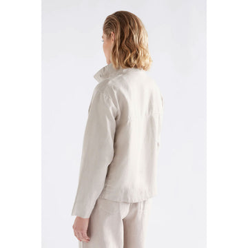 Woman wearing a beige jacket and pants on a white background.