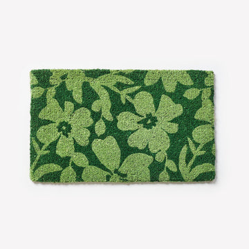 A green door mat printed with light green flowers.