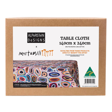 A brown box with the large label on the front with the text 'Table Cloth' and a photo of the table cloth inside featuring artwork by Gladys Kuru Bidu.