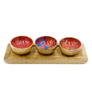 Three small wooden bowls on a wooden board. The inside of the bowls is printed with artwork by Andrea Adamson.