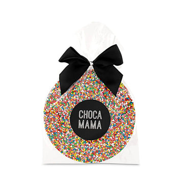 A round chocolate covered with sprinkles inside clear packaging with a black bow on the top.