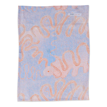 A linen tea towel printed with orange and purple Indigenous artwork.