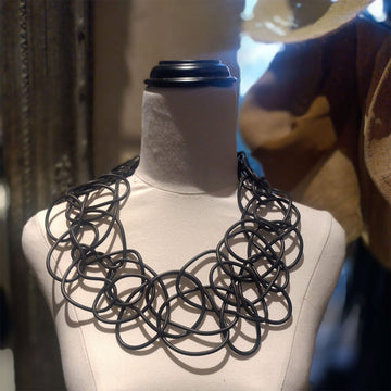 A black necklace made up of looped rubber on a mannequin.