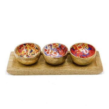 Three small wooden bowls on a wooden board. The inside of the bowls is printed with artwork by Stephen Nelson.