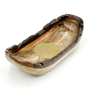 A wooden bowl with rigid edges and a round gold medallion in the middle of the bowl.