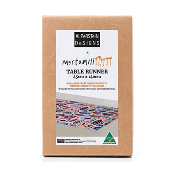 A brown box with a large product label on the front with a photo of the table runner inside illustrated with artwork by Gladys Kuru Bidu.