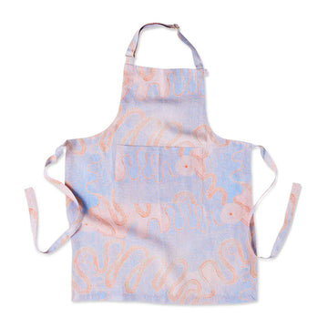 A linen apron printed with an orange and purple Indigeneous print.