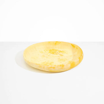 A large round shallow bowl made from yellow resin.