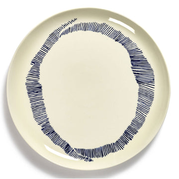 Top down view of a ceramic plate in white with dark blue stripes around the edge.