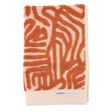 A folded up hand towel with an embossed orange pattern.