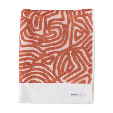 A folded up bath towel embossed with an orange pattern.
