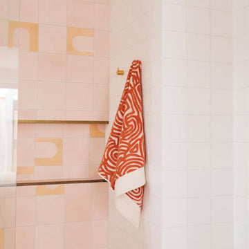 A folded up bath towel embossed with an orange pattern.