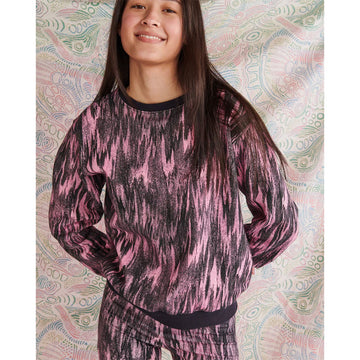 Close up front view of a model wearing a matching sweater and leggings in a pink and black pattern.