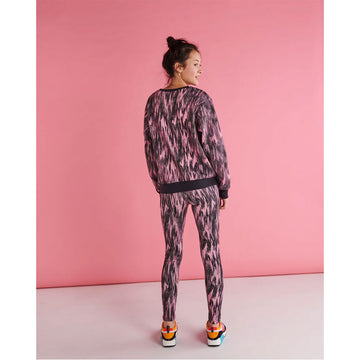 Close up front view of a model wearing a matching sweater and leggings in a pink and black pattern.