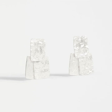 Pair of silver square earrings on a light gray background.
